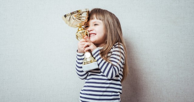 Little girl holding a trophy and smiling