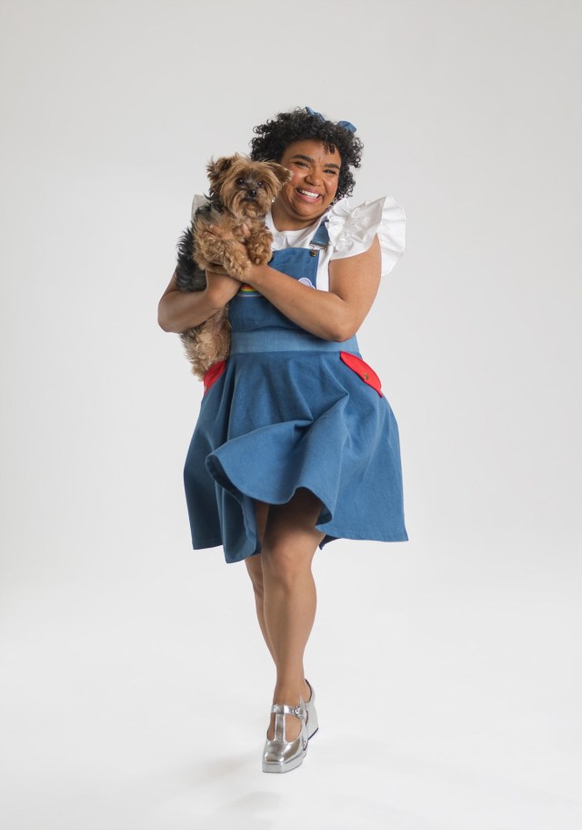 an actor dressed as Dorothy holding Toto as part of the shows in seattle 5th avenue theater production of The Wiz