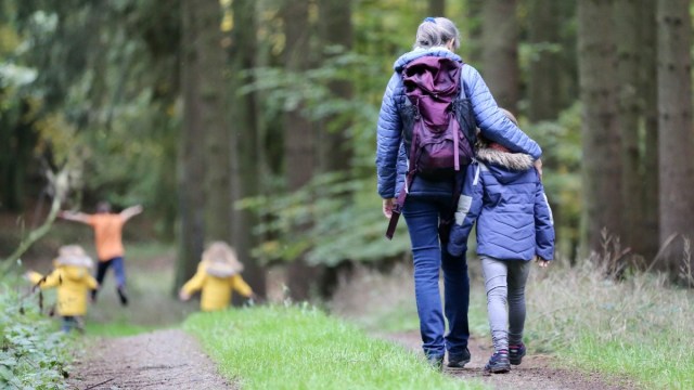 a woman has her arm around a child and they are hiking through the forest during a winter hike near portland