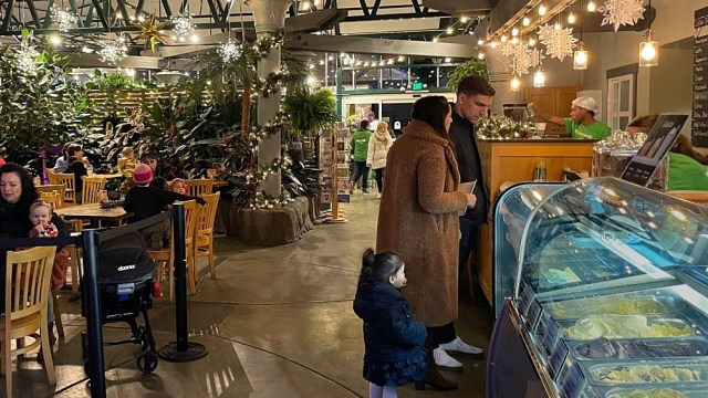 a couple and a child browse food items at swanon's nursery in seattle a christmas decorated restuarant with their child