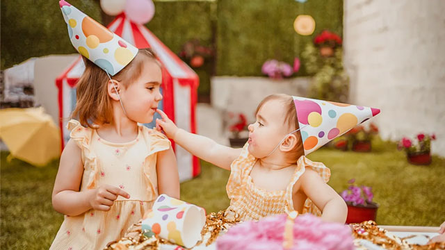 A picture of a baby with her big sister celebrating with a circus party, one of the cutest first birthday party ideas