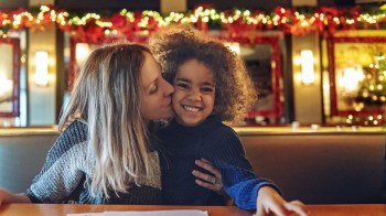 a mom gives a kid a kiss at a christmas decorated restaurant in seattle aromory