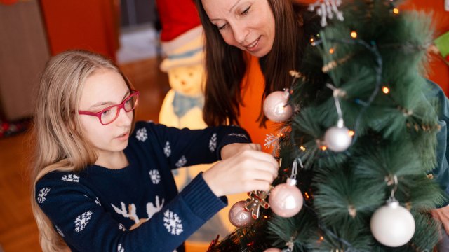 teen decorating Christmas tree with mom