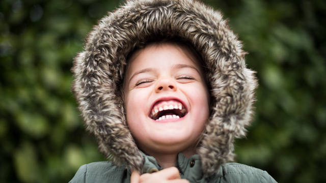 boy in a coat laughing at winter jokes for kids
