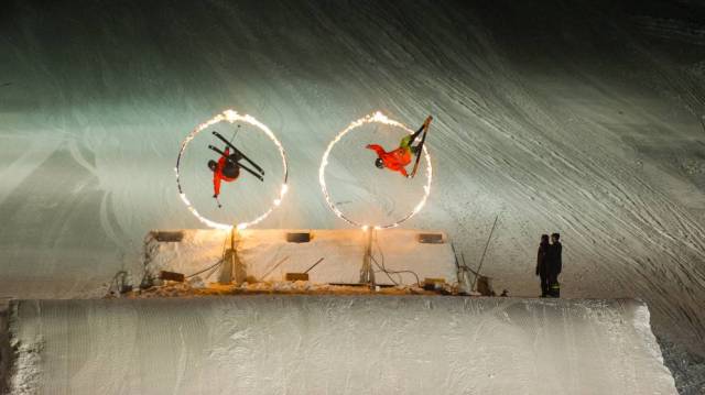 two skiers jump through hoops of fire