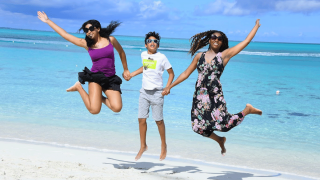 family jumping for joy on beach in winter