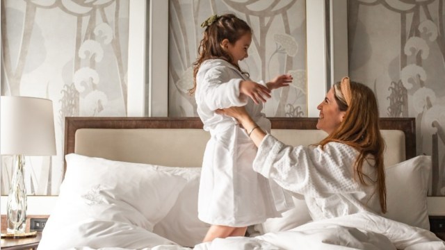 a mother and daughter play on a bed at the four seasons one of the best hotels in boston for families, family-friendly hotels