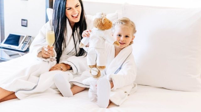 Mom and daughter having spa day while sitting in bed in white robes