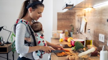 mom cooking from an easy meal delivery service while wearing her baby