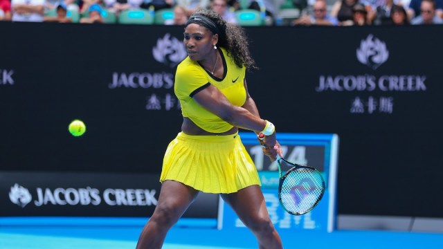 Serena Williams dressed in yellow hits a ball on the tennis court,