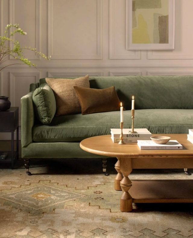 a living room with an olive green sofa, coffee table, and candle sticks