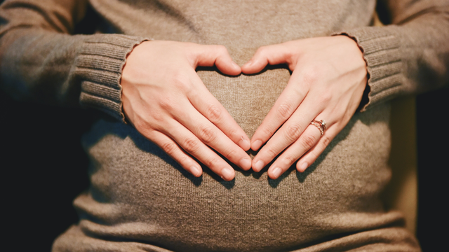 mom making a heart shape on her pregnant belly