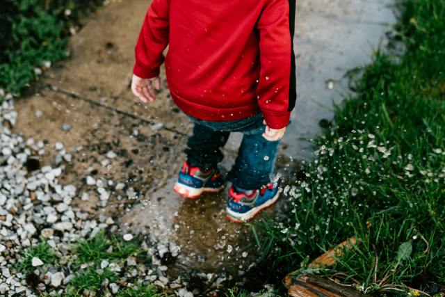 Boy jumping in rain puddles.