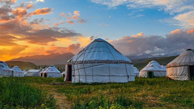 Yurt village in a green field and sunset