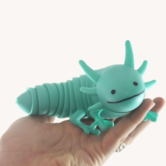 a hand holding a teal axolotl toy