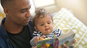 a dad and child reading a books for newborns in a chair together