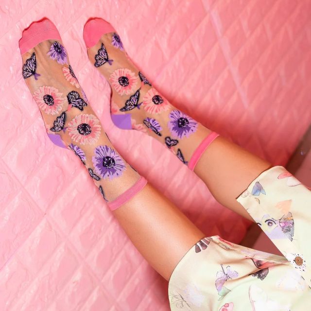a person's legs propped against a pink wall wearing sheer floral socks