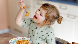 a picky eating little girl having pasta with tomato sauce
