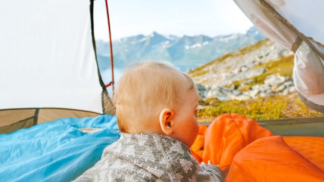 baby in camping tent looking out over mountains