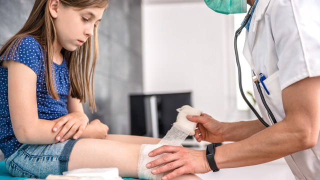 an ER pediatrician bandages a young girl