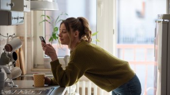 woman looking at her phone in the kitchen