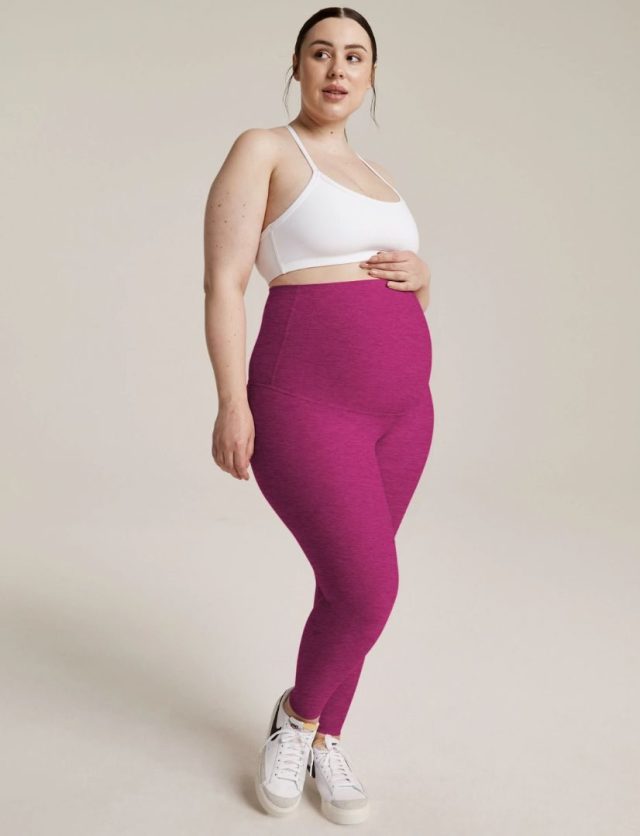 pregnant woman standing in pink workout leggings and white sports bra