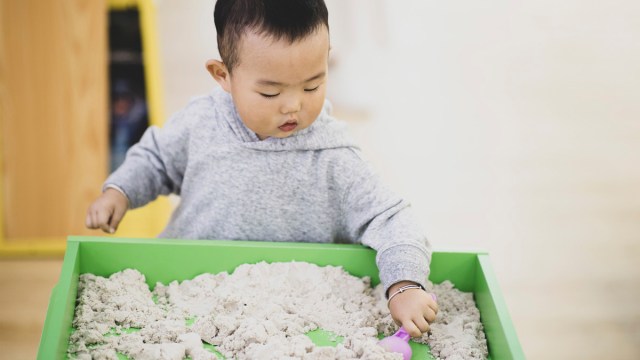 a baby boy playing with sand for a story on sensory activities for toddlers and babies