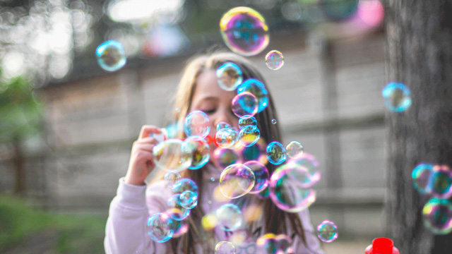 little girl playing sidewalk games with bubbles