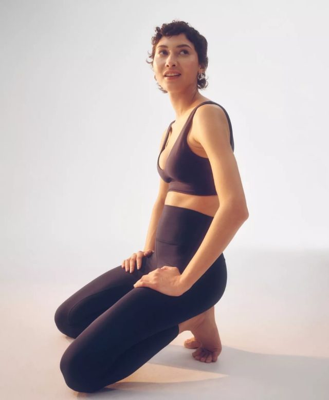 woman in leggings and sports bra kneeling