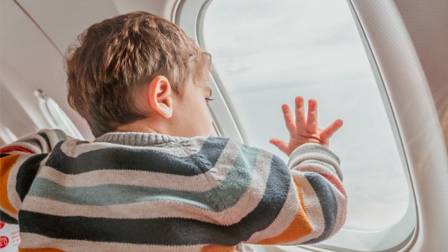 a toddler boy looking out the airplane window for a story on traveling with painter's tape