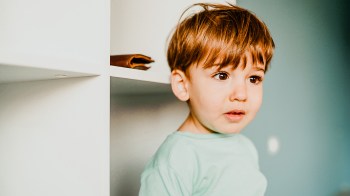 a little kid looking curious about something he's seeing, a parent changing in front of him