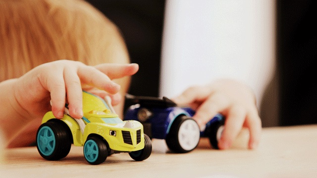 a child plays with a yellow toy car and a blue one while waiting, waiting games