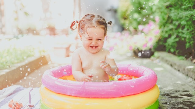 a baby splashing in a kiddie pool for some outdoor water play