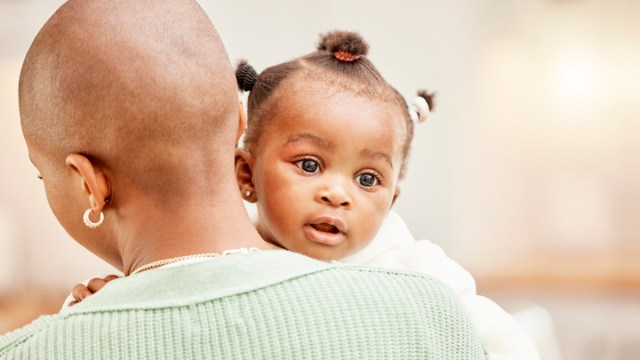 Parent holding a baby with pierced ears who had infant ear piercing