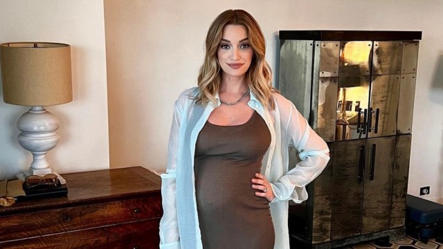 Brianne Howey posing in a bodycon dress that shows her baby bump