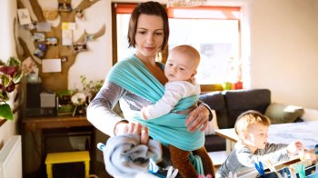 mom wearing her baby in a sling practicing attachment parenting
