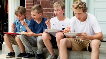 tween boys sitting on a stoop and eating food