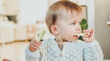 A toddler eating cucumber sticks, which are actually a choking hazard