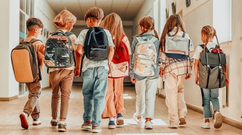 a group of kids in backpacks walking in their school without their names on their backpacks, a top back-to-school safety tip