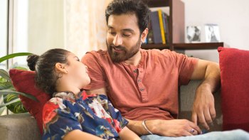 dad talking to his daughter after school on the couch