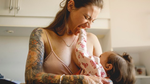 a mom with tattoos breastfeeding her baby for a story answering 'can you get a tattoo while breastfeeding'