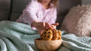 girl reaching for a bowl of cookies for dinner