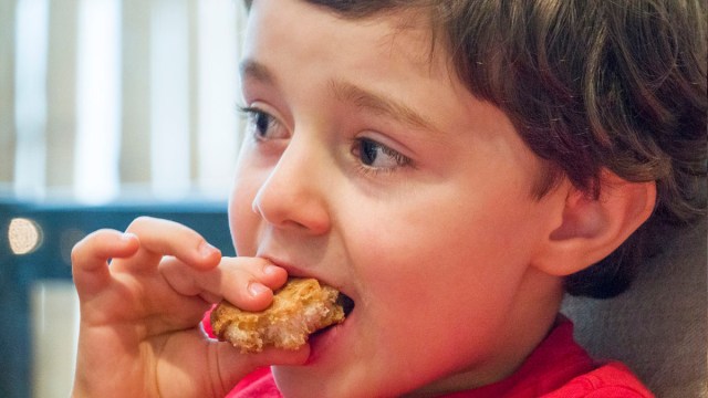 a kid eating a chicken nugget