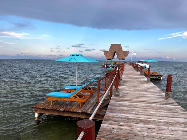 Looking out to the dock. Lounge chair areas are on either side, with blue umbrellas and cushions.