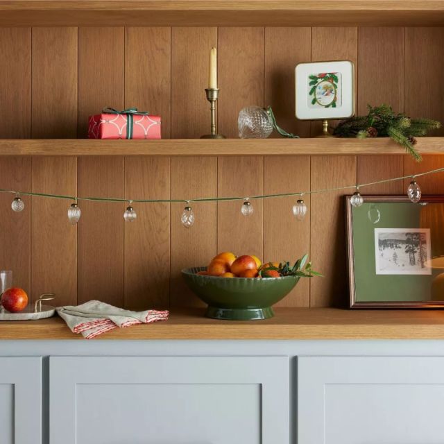 kitchen hutch holiday display featuring mini glass ornaments and dark green cord