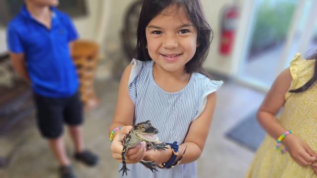 smiling girl in blue dress holding baby alligator at Gatorland in Orlando, Florida