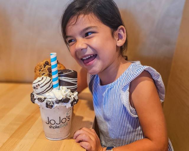 girl smiling over large chocolate milkshake at JoJo's ShakeBAR in Orlando, Florida