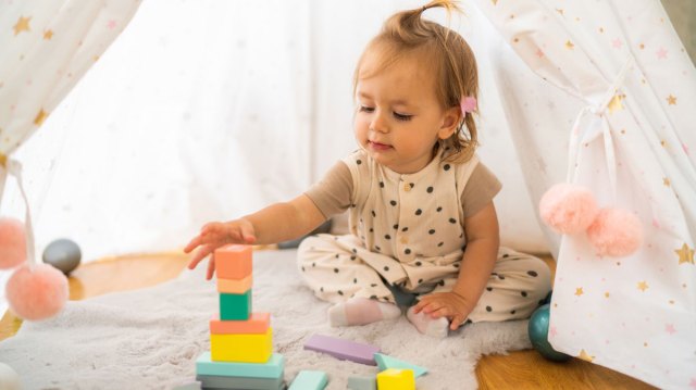 toddler girl playing with blocks by herself
