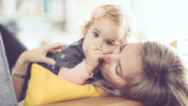 a little girl sucking her thumb while lying on her mom who is trying to figure out how to stop thumb sucking