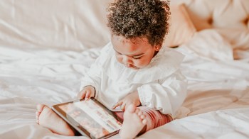 A baby girl playing on an ipad for a story on babies and screen time